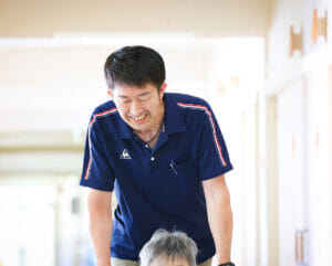 介護職員が入居者と関わる様子。廊下での日常的なケアシーン